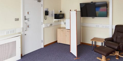 The Family Room at Hinxton Hall Conference Centre, showing comfortable seating, a padded play area, microwave, fridge, highchair, and a screen The Family Room at Hinxton Hall Conference Centre, showing comfortable seating, a padded play area, microwave, fridge, highchair, and a screen